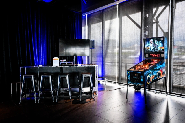 Video game area with a Nintendo Switch lounge and bar section to the left and a pinball machine to the right.