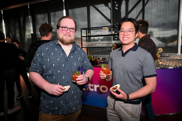 Two male guests posing with their appetizers and drinks.