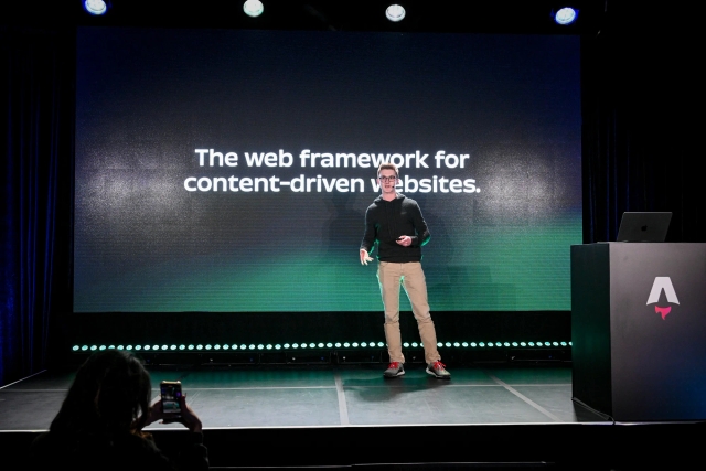 Ben Holmes on stage in front of a slide that reads, "The web framework for content-driven websites."