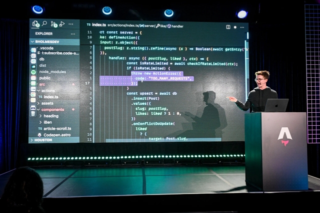 Ben Holmes on stage at the podium, sharing a demo. He is live-coding.