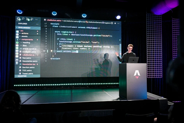 Ben Holmes speaking from an Astro-branded podium. His hand points to a code example of a like button component