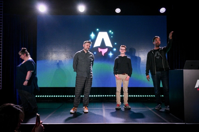 Keynote speakers on stage. From left to right: Sarah Rainsberger, Matthew Phillips, Ben Holmes, and Fred K. Schott (next to the podium). Sarah can be seen walking farther to the left. Fred gestures towards the audience.