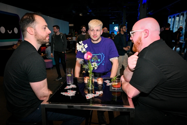 Astro team members chatting with their drinks at a high table.