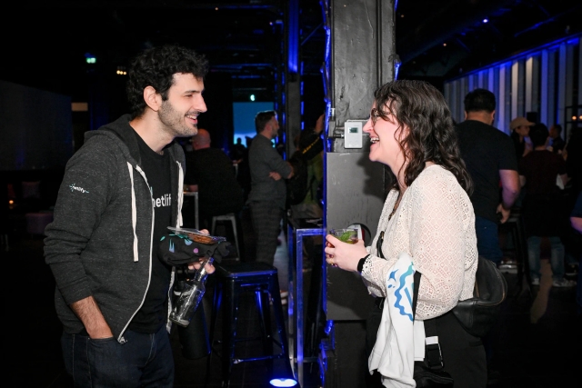 Two guests smile and laugh as they chat with one another.