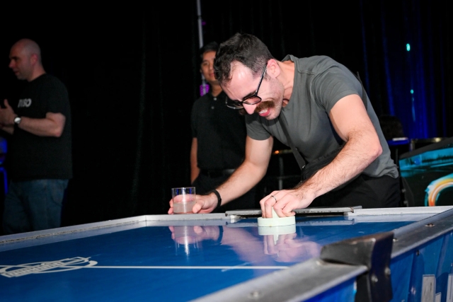 A guest smiles brightly as they play air hockey.